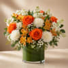 Orange roses and white carnations in a glass vase