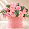 Pink roses arranged in a round pink box with eucalyptus accents