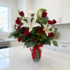 Bouquet of red roses and white lilies in a glass vase with a red ribbon