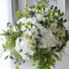 White hydrangea bouquet with purple bell-shaped flowers and green accents