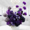 Purple orchid arrangement in a white vase