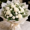 Creamy white roses and petite white carnations form a serene, rounded bouquet