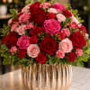 A lush cluster of red and pink roses with soft carnations creates