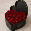 Tightly clustered, velvety red roses set inside a matte black heart-shaped box