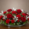 A tightly clustered low event arrangement of vivid red roses and red