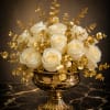 A lavish cluster of white roses arranged in a reflective gold pedestal