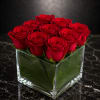 Red roses arranged in a clear square glass vase
