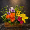 Bright mixed flower arrangement in a wooden box with orange roses and yellow lilies
