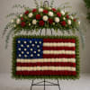 Standing floral tribute shaped like the U.S. flag on an easel