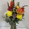 Mixed bouquet in a clear glass vase with roses, carnations, and daisies