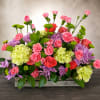 A lush, garden-style centerpiece overflowing with color, this flower arrangement is perfect