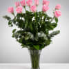 Pink roses arranged in a clear glass vase with mixed greenery