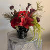 Red and purple floral arrangement in a black skull vase