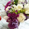 Bouquet of white roses, purple daisies, and lavender filler tied with a purple ribbon