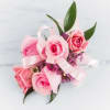 Pink rose corsage with ribbon and small purple accents