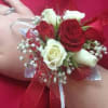 Red and white rose wrist corsage with ribbon on a person's wrist