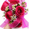 Handheld bouquet of hot pink roses with small white blossoms and pink ribbon
