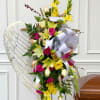 Tall floral standing spray with yellow and pink flowers on an easel