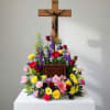 Colorful funeral floral arrangement beneath a wooden crucifix