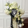 White floral standing spray with lilies and a Raiders emblem