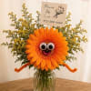 Orange gerbera daisy arrangement with a playful face in a glass vase