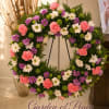 Circular floral wreath with pink, purple, white, and green blooms on a stand