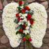 Heart-shaped white floral wreath with red roses and lilies