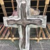 A distressed wooden cross on a display stand creates a peaceful focal