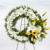 White and yellow floral wreath on a stand