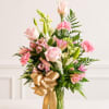Pink roses and lilies arranged in a glass vase with a gold ribbon