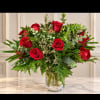 Red roses in a clear glass vase with lush greenery