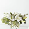 White lily bouquet in a clear glass vase with mixed white blooms and greenery
