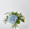 Blue hydrangea bouquet with white flowers in a clear glass vase
