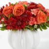 Orange roses and red chrysanthemums in a white pumpkin vase