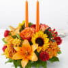 Orange floral centerpiece with two tall orange candles