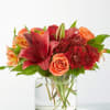 Red and orange floral arrangement in a clear glass vase