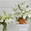 White floral arrangements in a glass vase and wicker basket