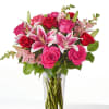 Bouquet of pink and red roses with lilies in a clear glass vase