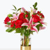 Bouquet of red roses and pink lilies in a clear glass vase