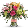 Pink and peach roses with lilies and green hydrangeas in a glass vase