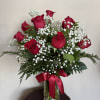 Red roses with white baby's breath in a glass vase tied with a red ribbon