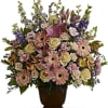 Tall arrangement of pink lilies, gerbera daisies, and cream roses in a brown urn-style vase