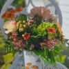 Mixed bouquet in a painted white mug with orange and pink flowers.