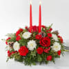 Red candle centerpiece with white and red flowers and pinecones