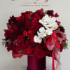 Red rose and orchid arrangement in a burgundy hat box with ribbon