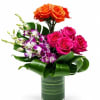 Bouquet of orange and pink roses with purple orchids in a glass vase