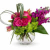 Pink roses and purple flowers in a clear glass vase