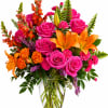 Bright mixed bouquet of pink roses, orange lilies, and orange snapdragons in a glass vase