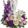 Purple and white floral arrangement with an angel figurine