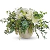 White roses and lilies in a low ceramic vase with trailing greenery